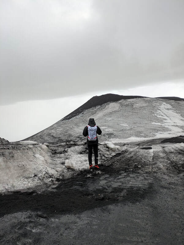 A walker looking out towards an extinct volcanic crater - Montagnola.